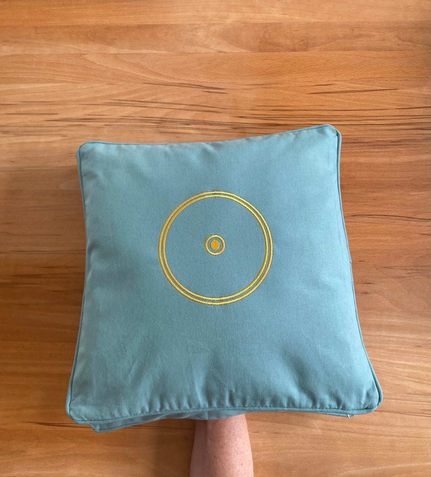 Orgon Kissen grün mit energetischem Schutz (Sonnensymbol) in der Anwendung auf der Hand & Handgelenk